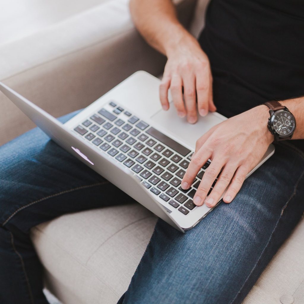 Man using laptop by sitting on couch - Carlogix Auto Transport Kissimmee FL